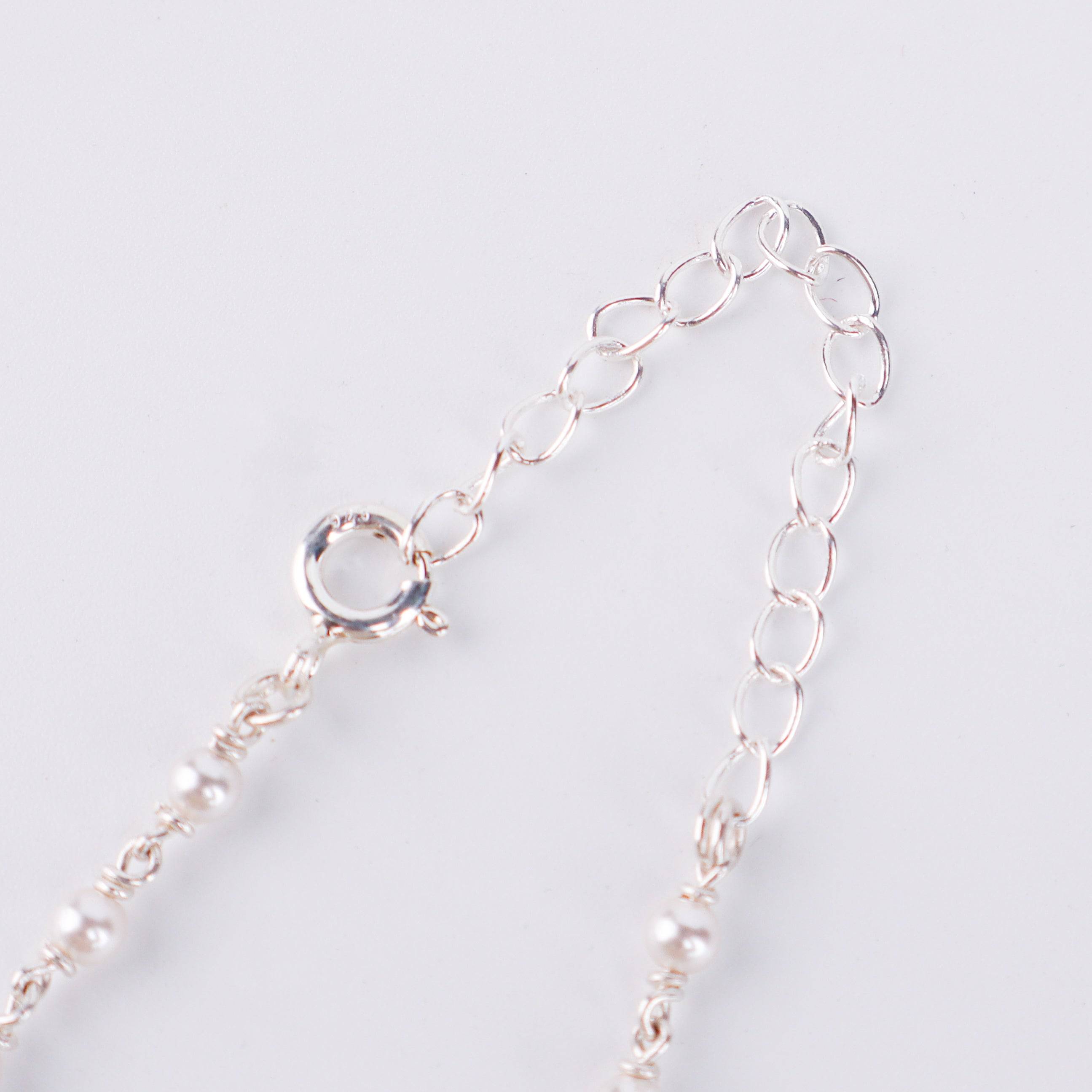 Flat-lay of 3mm pearl Gantan necklace on silk fabric with soft natural light