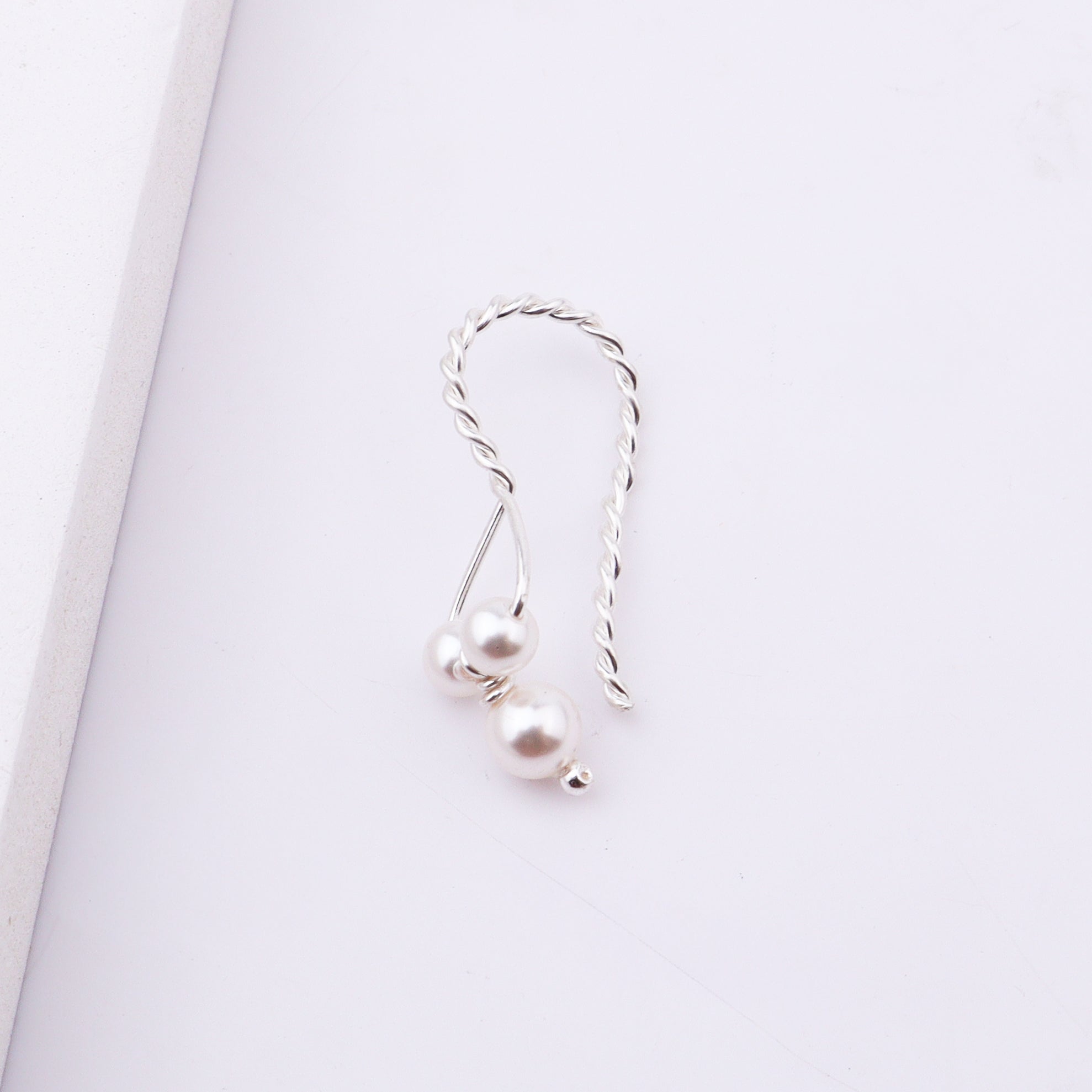Close-up of pearl earrings with silver twisted design