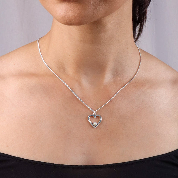 Woman wearing silver heart and pearl necklace