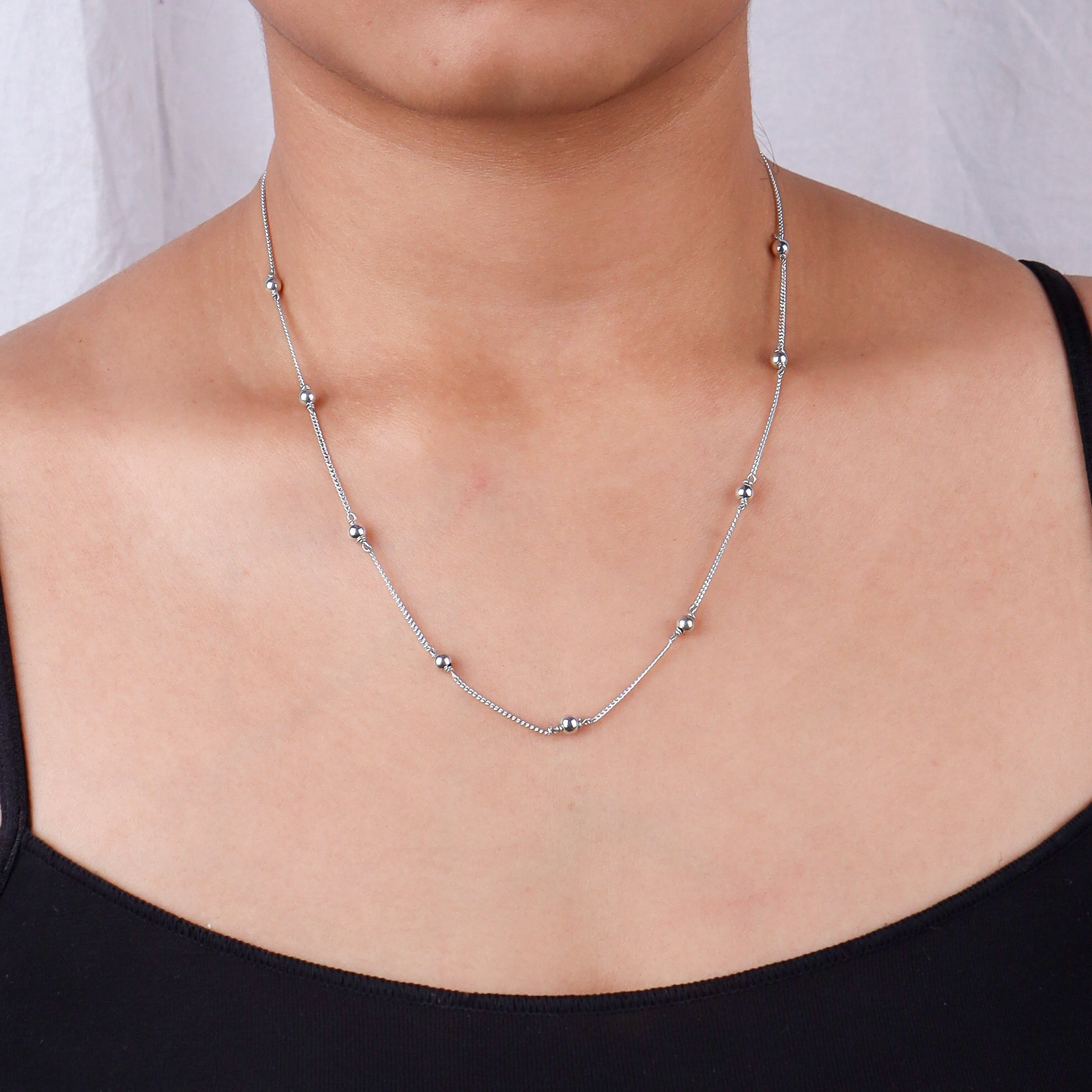 Silver beaded chain necklace on a woman's neck