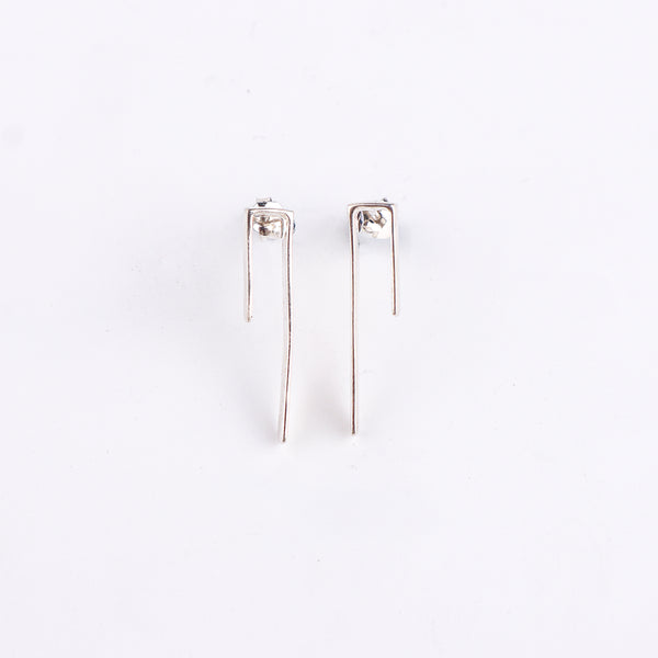 Silver asymmetric earrings on white surface