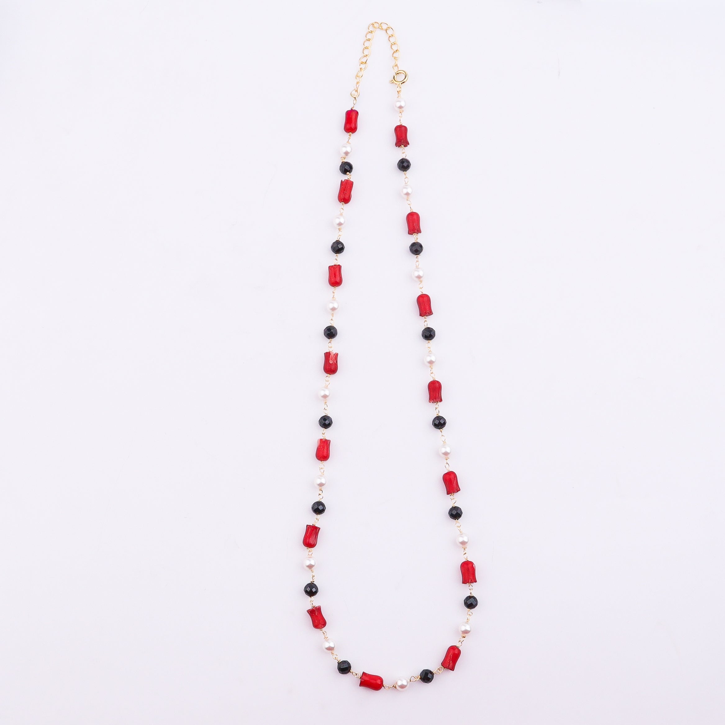 Beaded necklace with coral, pearl, and black spinel on white background