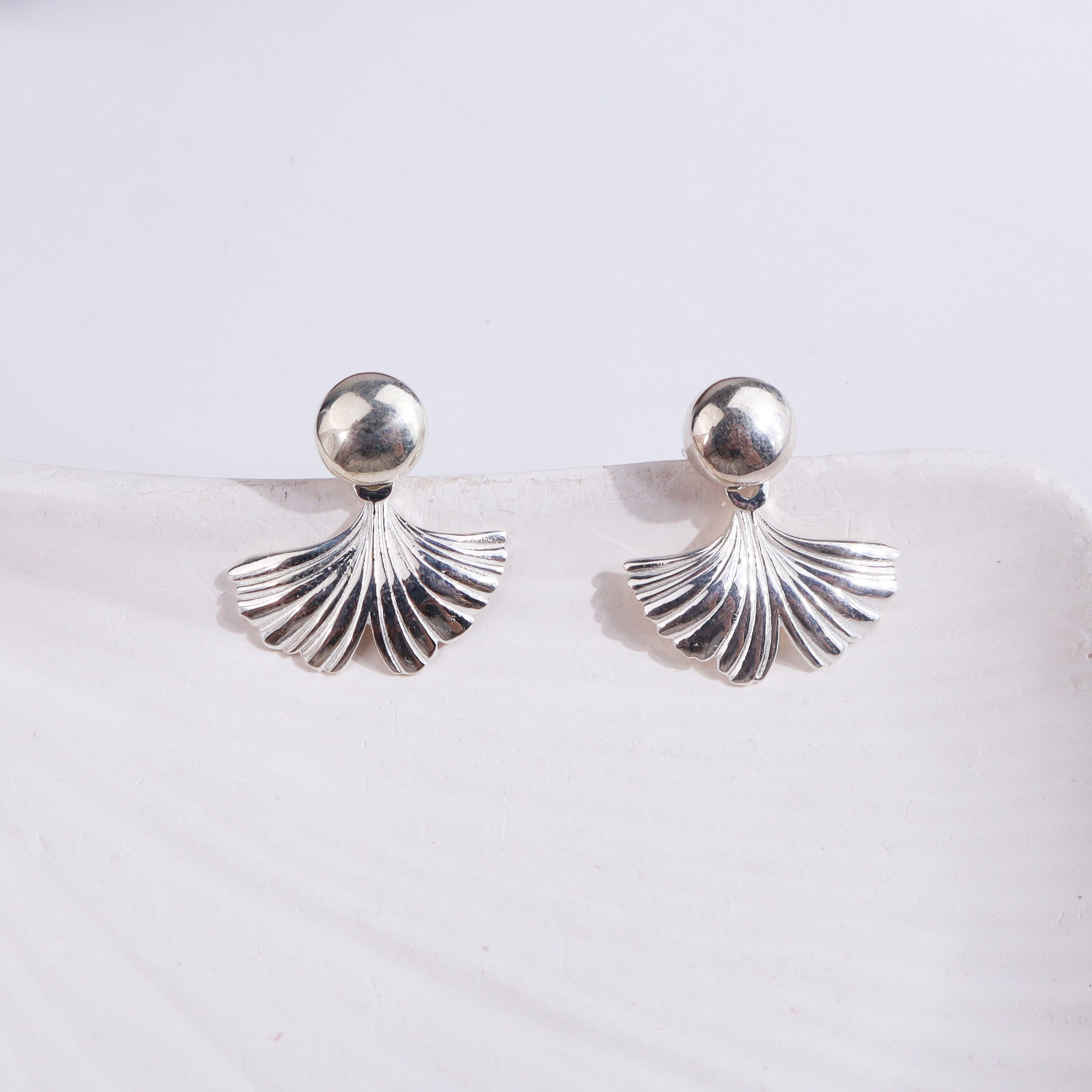 Silver earrings with leaf design on jewelry stand