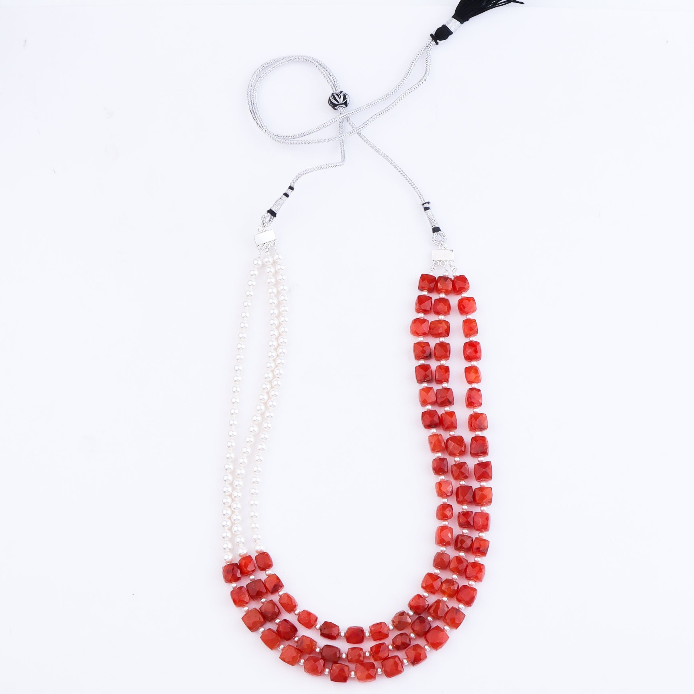 Silver chain necklace with red faceted beads on white background