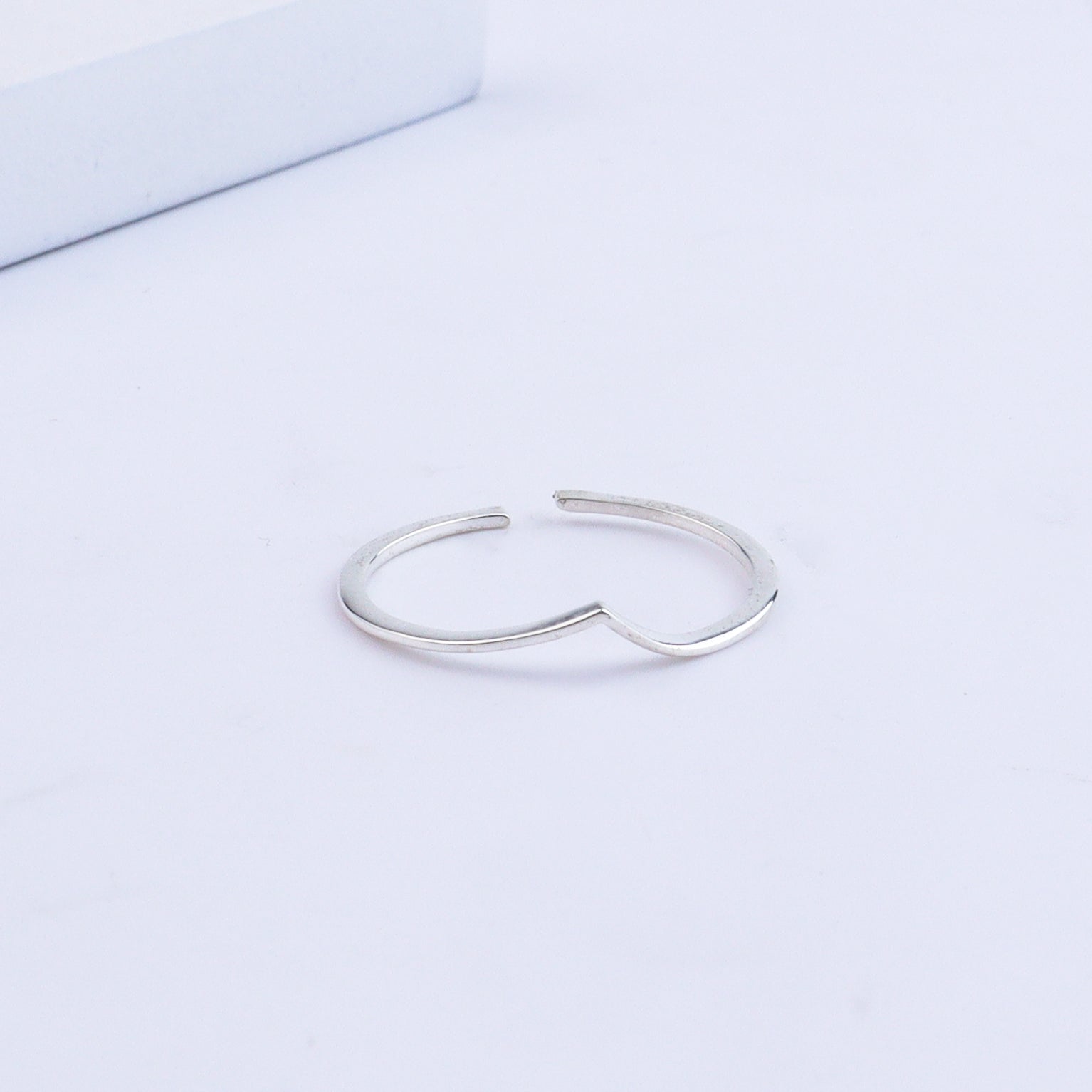 Silver heart-shaped ring on white surface