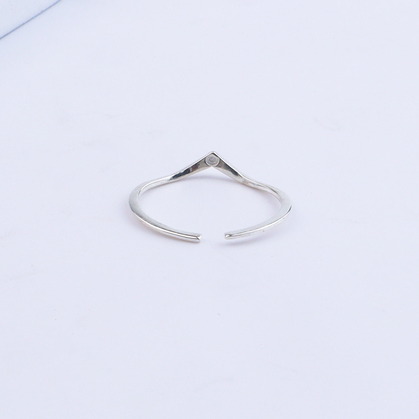 Silver V-shape ring displayed on white surface