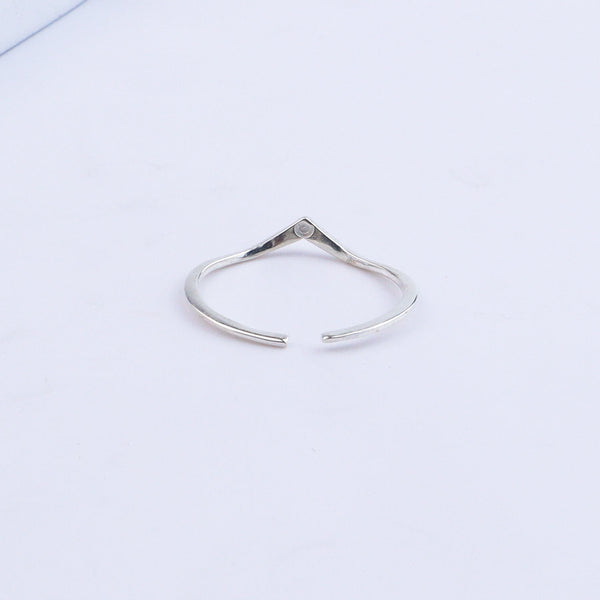 Silver V-shape ring displayed on white surface