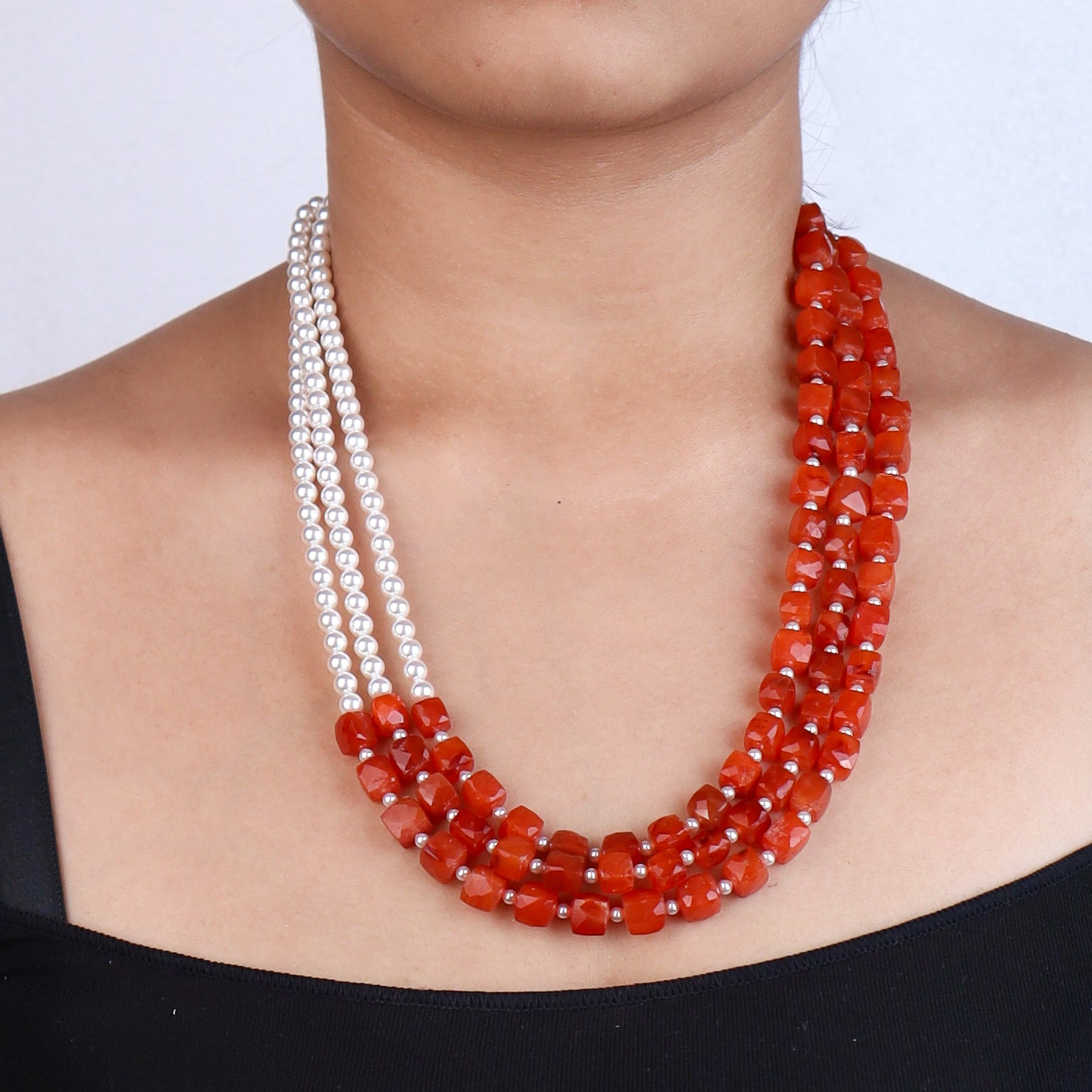 Close-up of white pearl and red beaded necklace on model