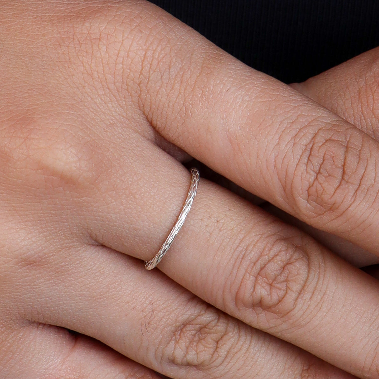 Silver textured ring worn on finger