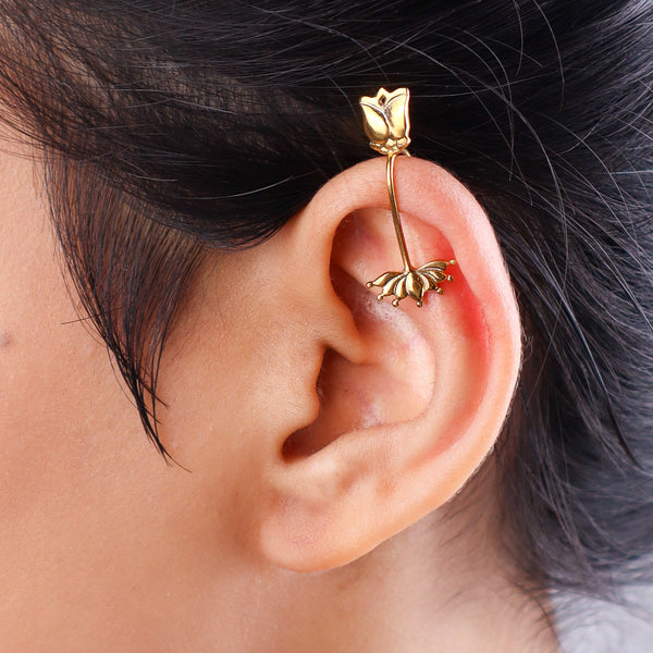Close-up of gold-tone lotus flower earring on white background