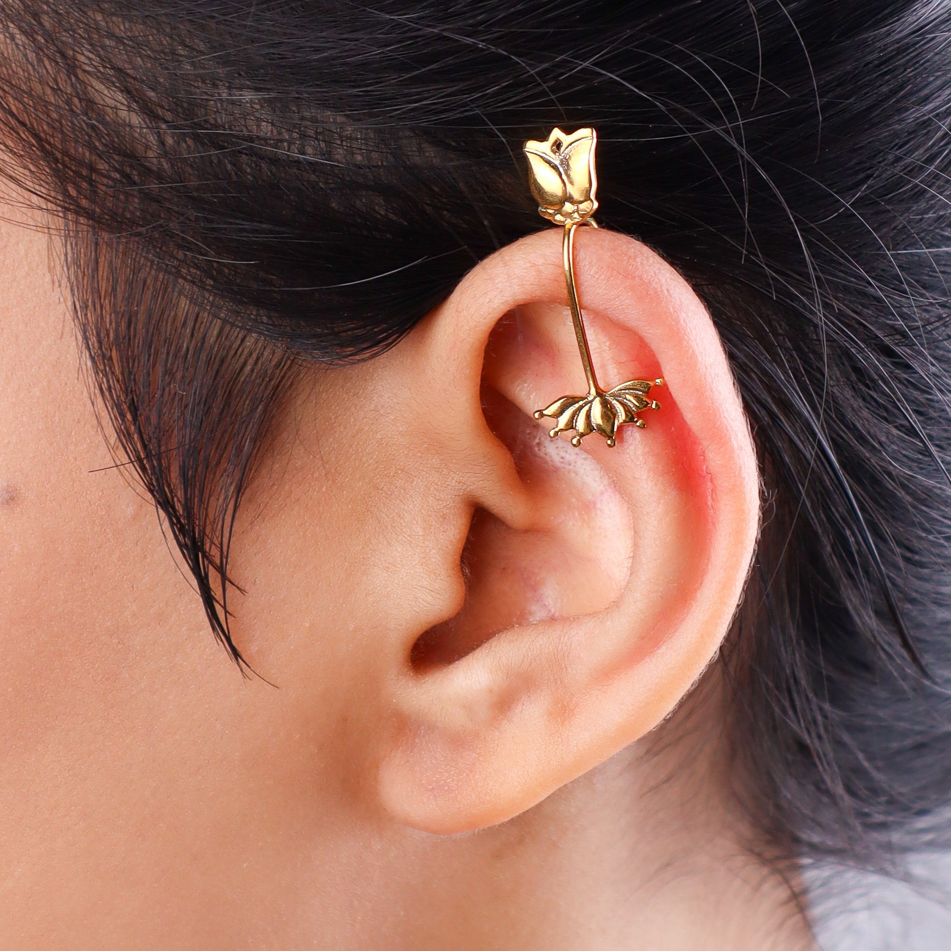 Close-up of gold-tone lotus flower earring on white background