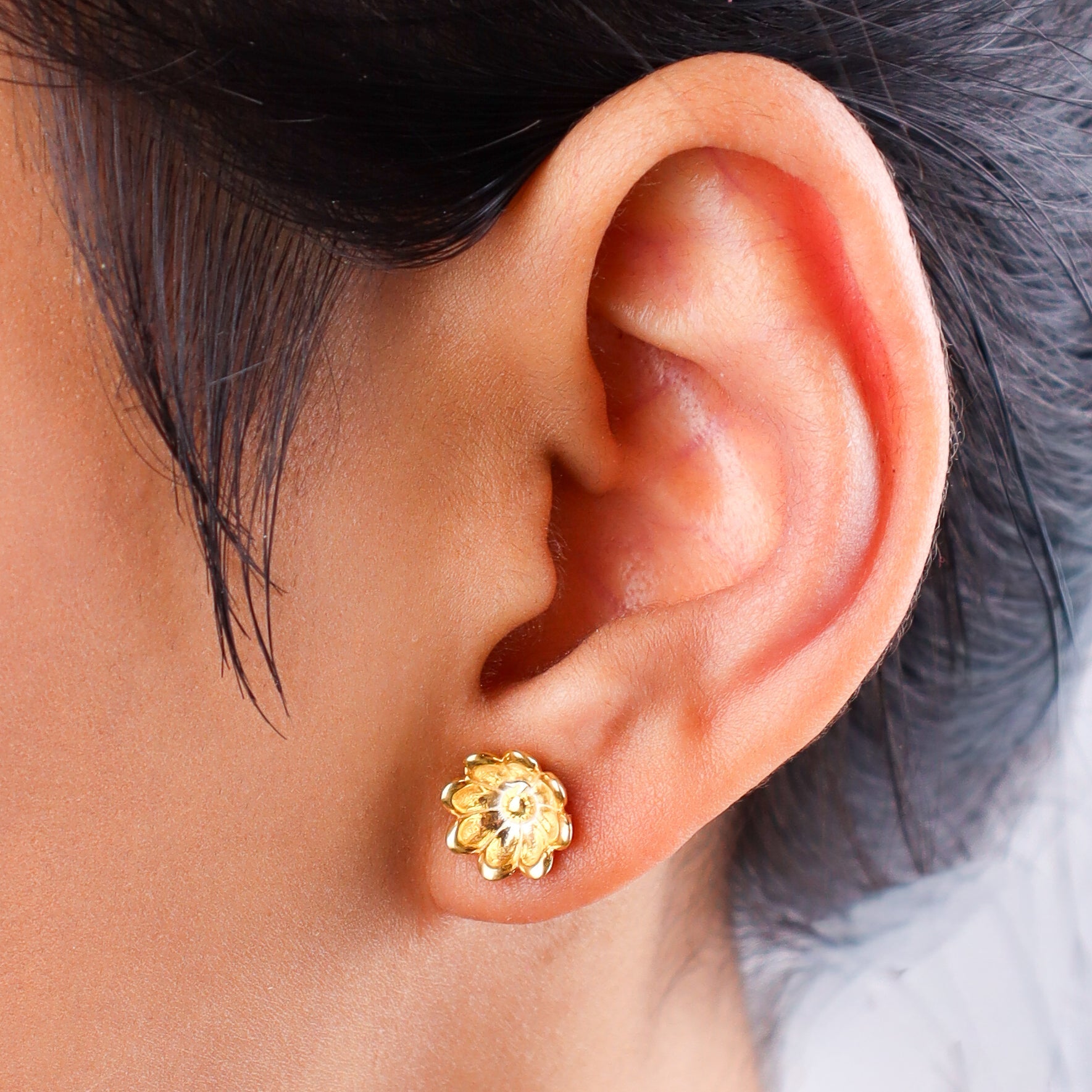 Close-up of gold flower stud earrings on white background