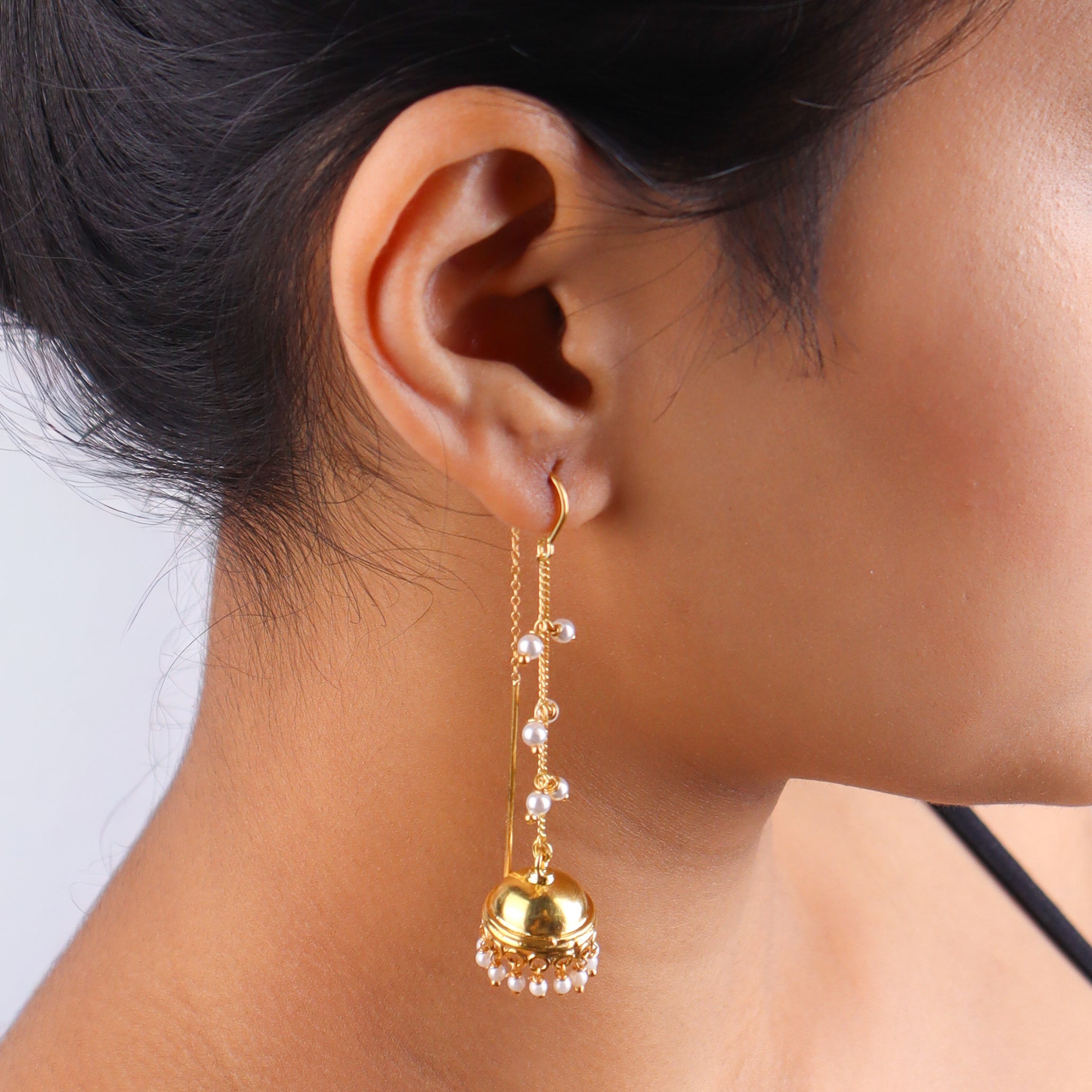 Close-up of gold chain earrings with pearl accents