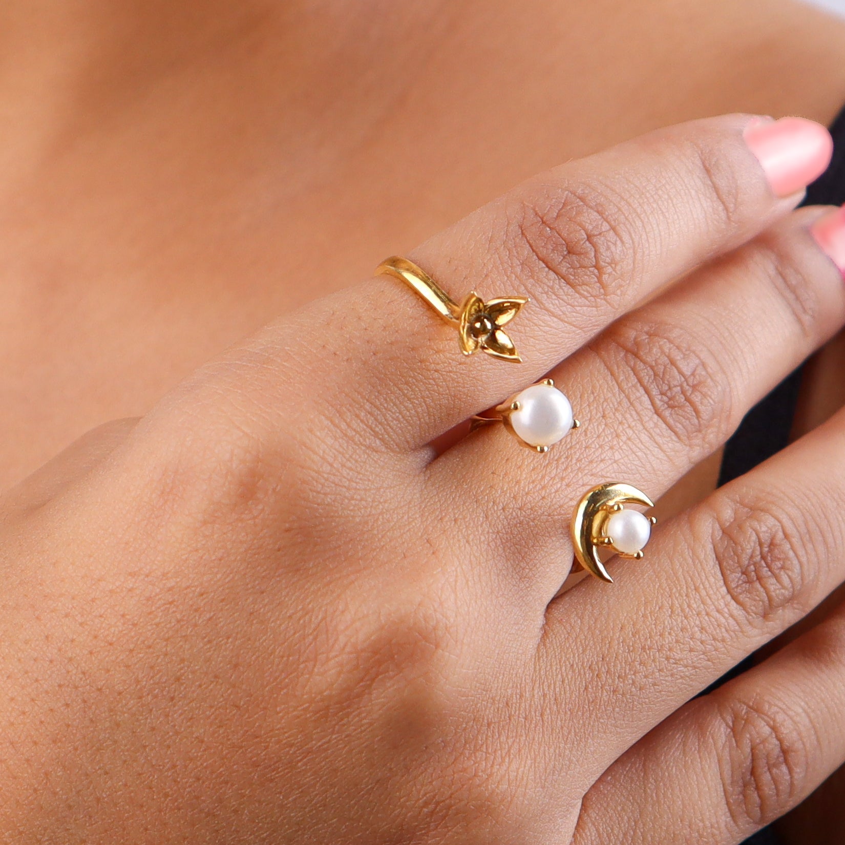 Close-up of gold moon and pearl ring on finger