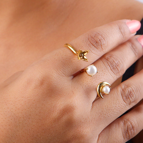 Close-up of gold moon and pearl ring on finger