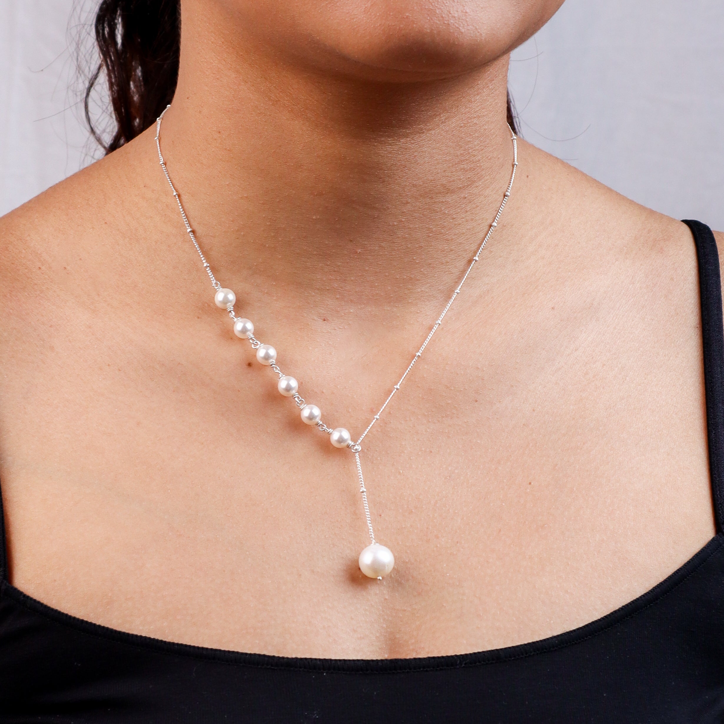Woman wearing silver pearl necklace with drop