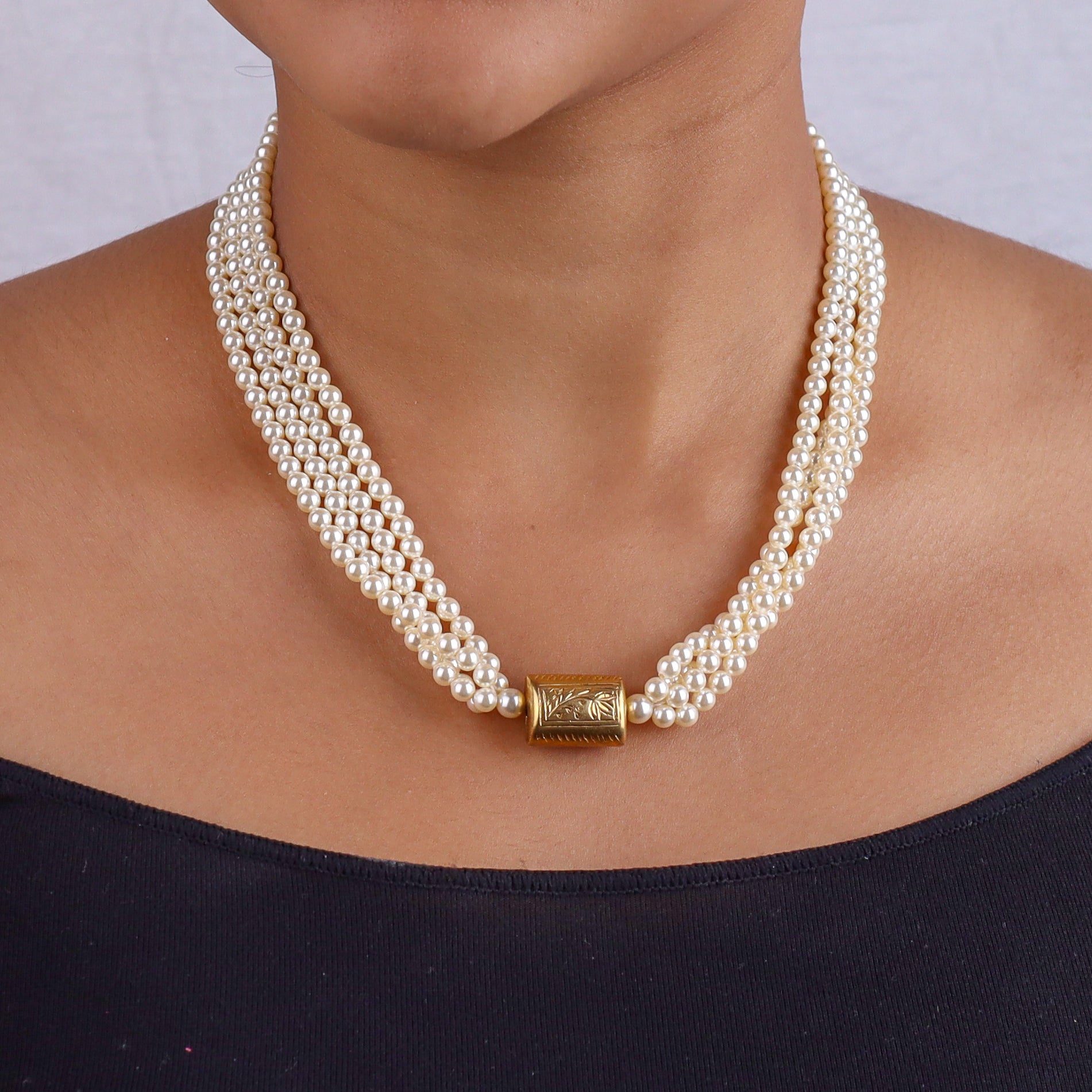 Pearl necklace on a model's neck with gold clasp detail