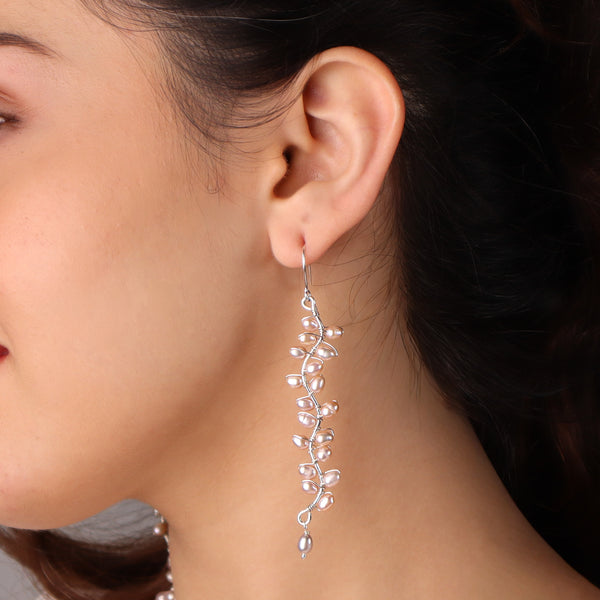 Angled side view of Heliconia pearl floral earrings showing elegant drop structure and secure fastening