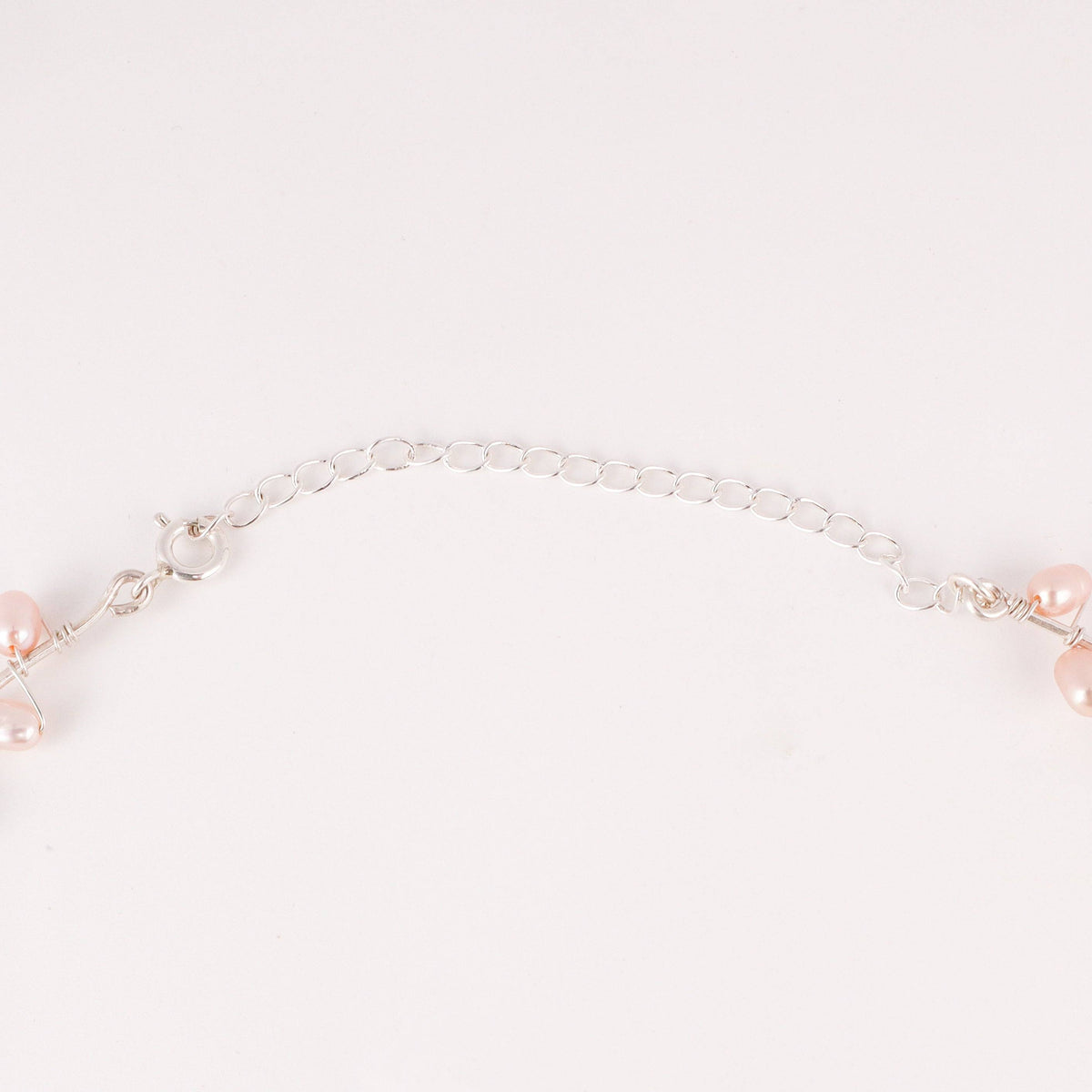 Flat-lay of fresh water pearl choker necklace on silk fabric with soft lighting