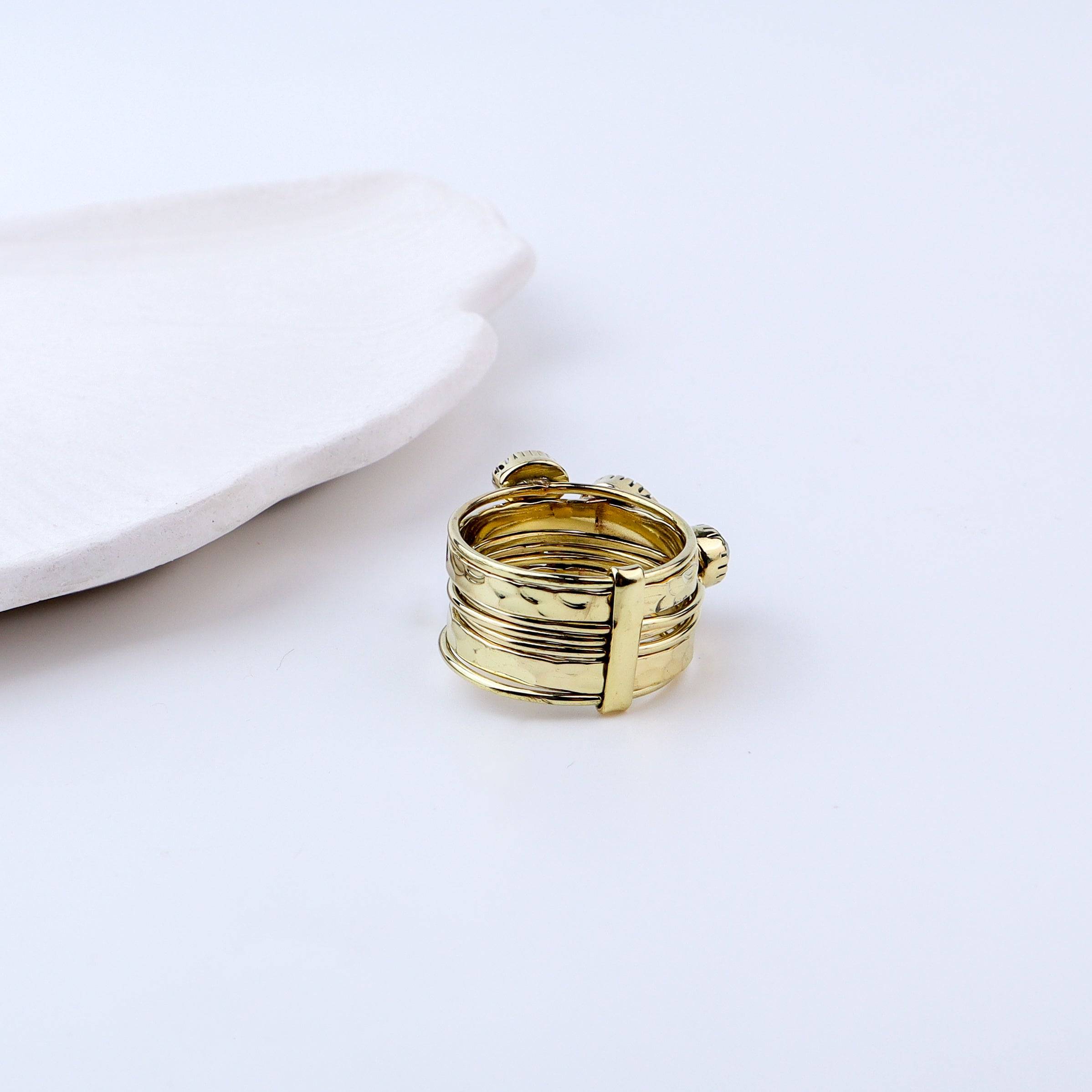 Angled view of a brass fashion ring highlighting its distinctive shape, structure, and polished brass finish