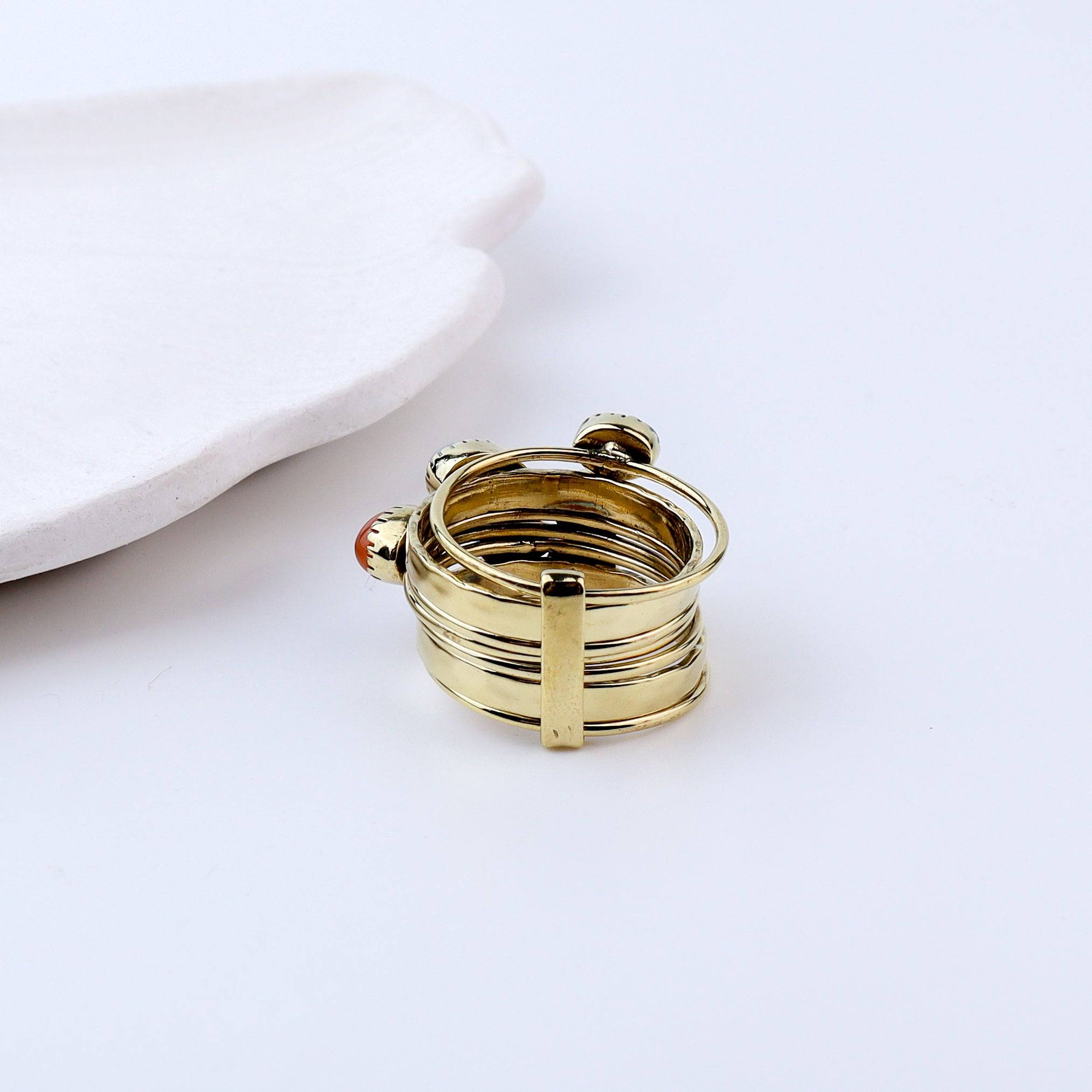 Angled view of a brass fashion ring highlighting its distinctive shape, structure, and polished brass finish