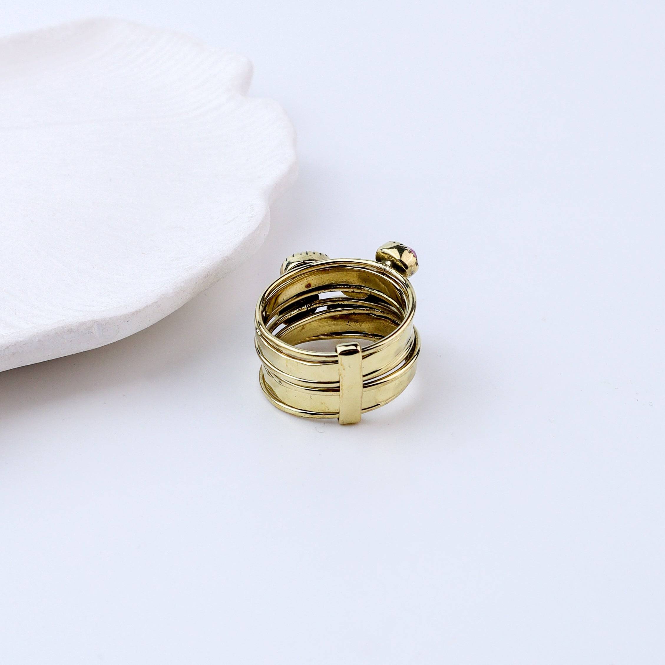 Angled view of a brass fashion ring highlighting its distinctive shape, structure, and polished brass finish