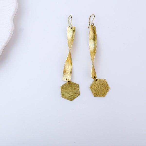 Detailed view of brass fashion earrings highlighting intricate motifs, textured surface, and refined brass finish
