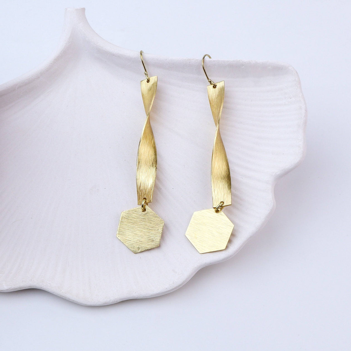 Angled view of brass fashion earrings highlighting the unique silhouette, structure, and polished brass finish