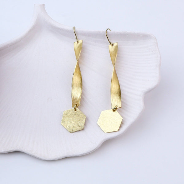 Angled view of brass fashion earrings highlighting the unique silhouette, structure, and polished brass finish