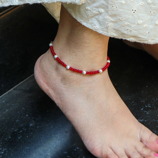 Close-up of red and white beaded anklet on ankle