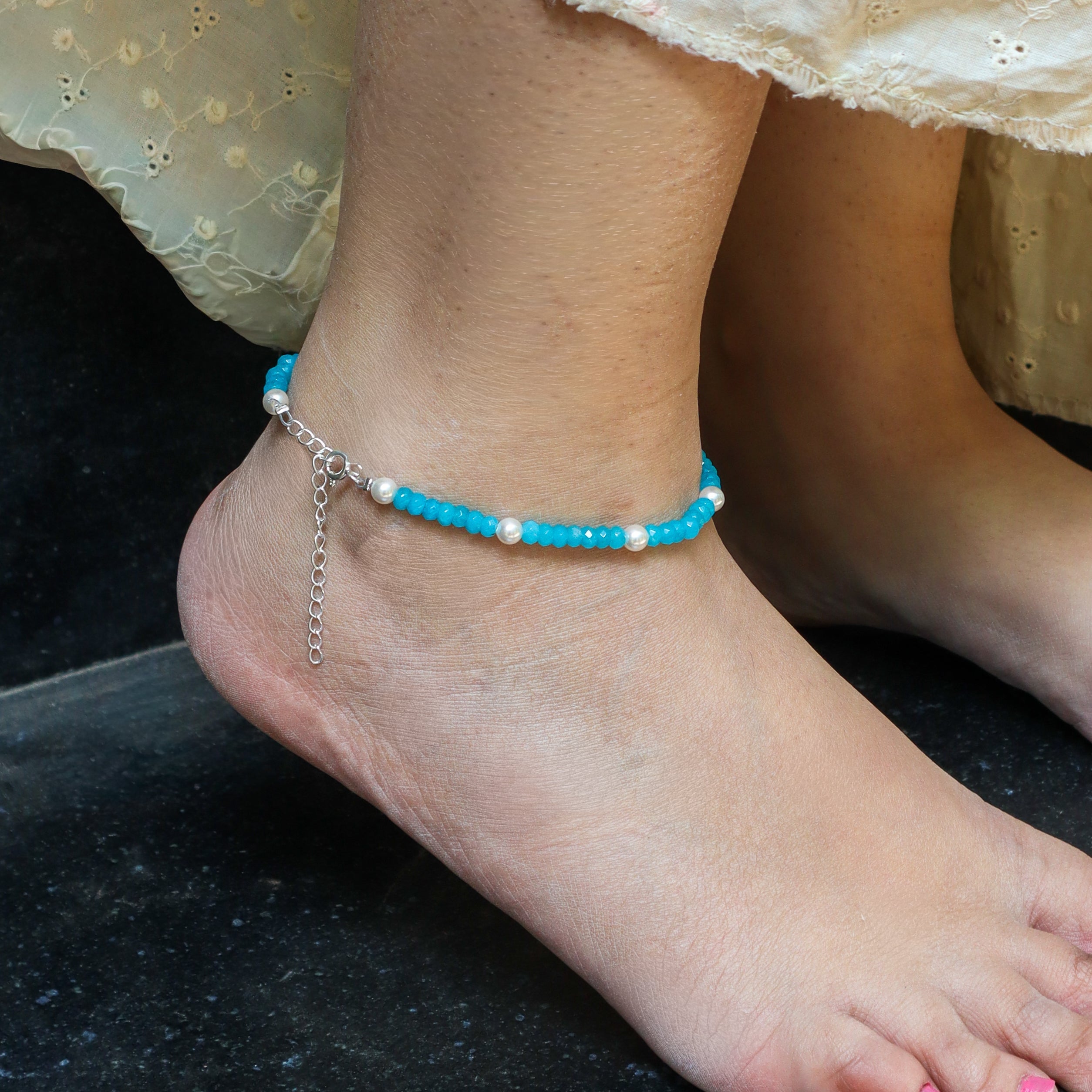 Close-up of blue beaded anklet with pearls