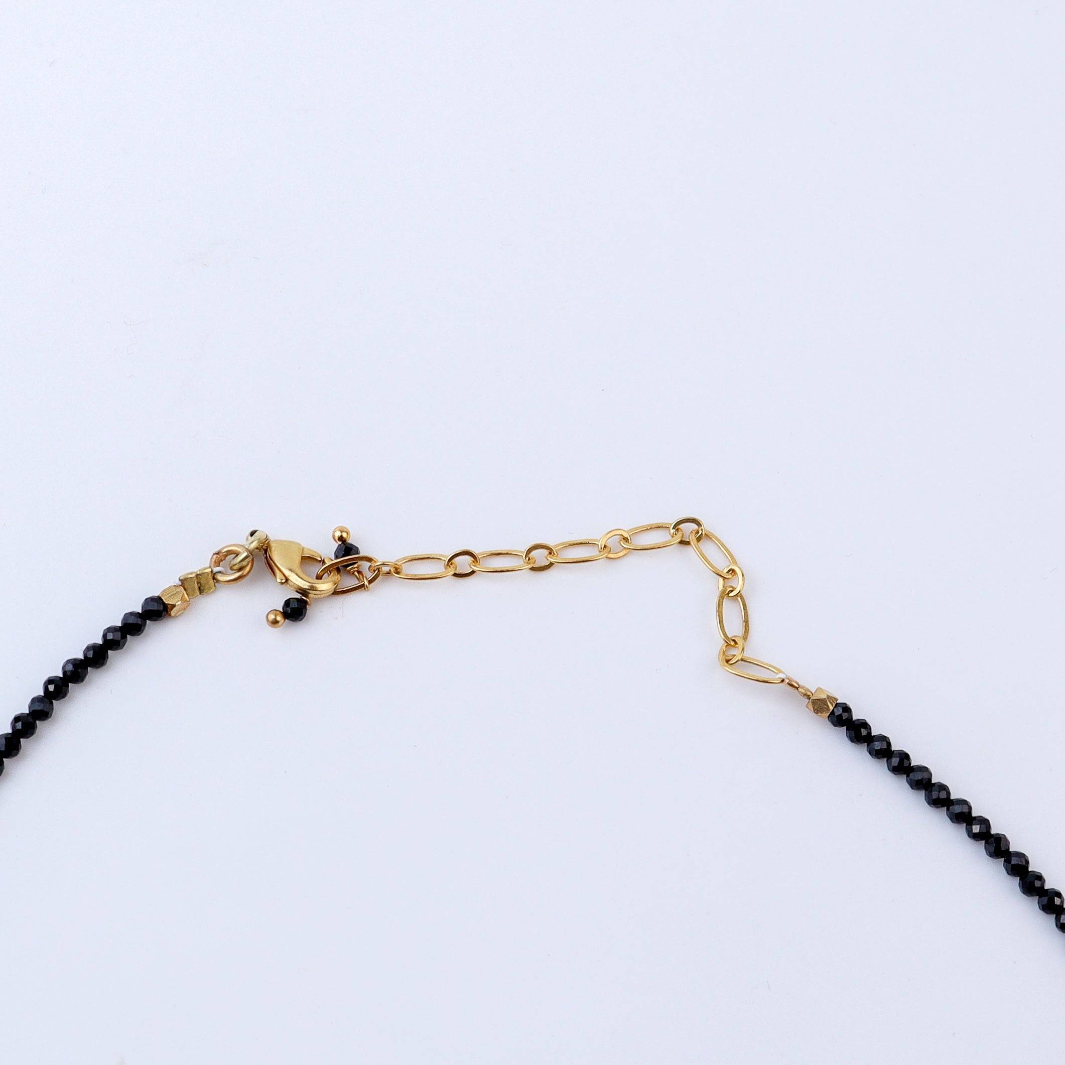 Angled view of a brass fashion necklace highlighting its unique silhouette, structure, and polished brass finish
