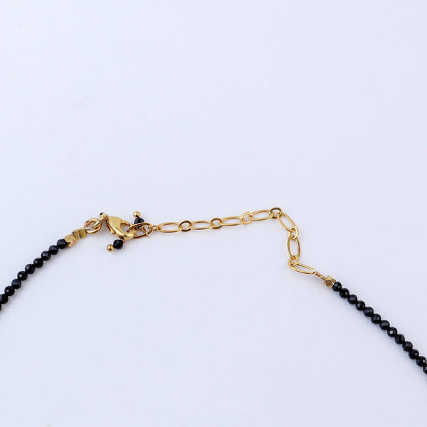 Angled view of a brass fashion necklace highlighting its unique silhouette, structure, and polished brass finish