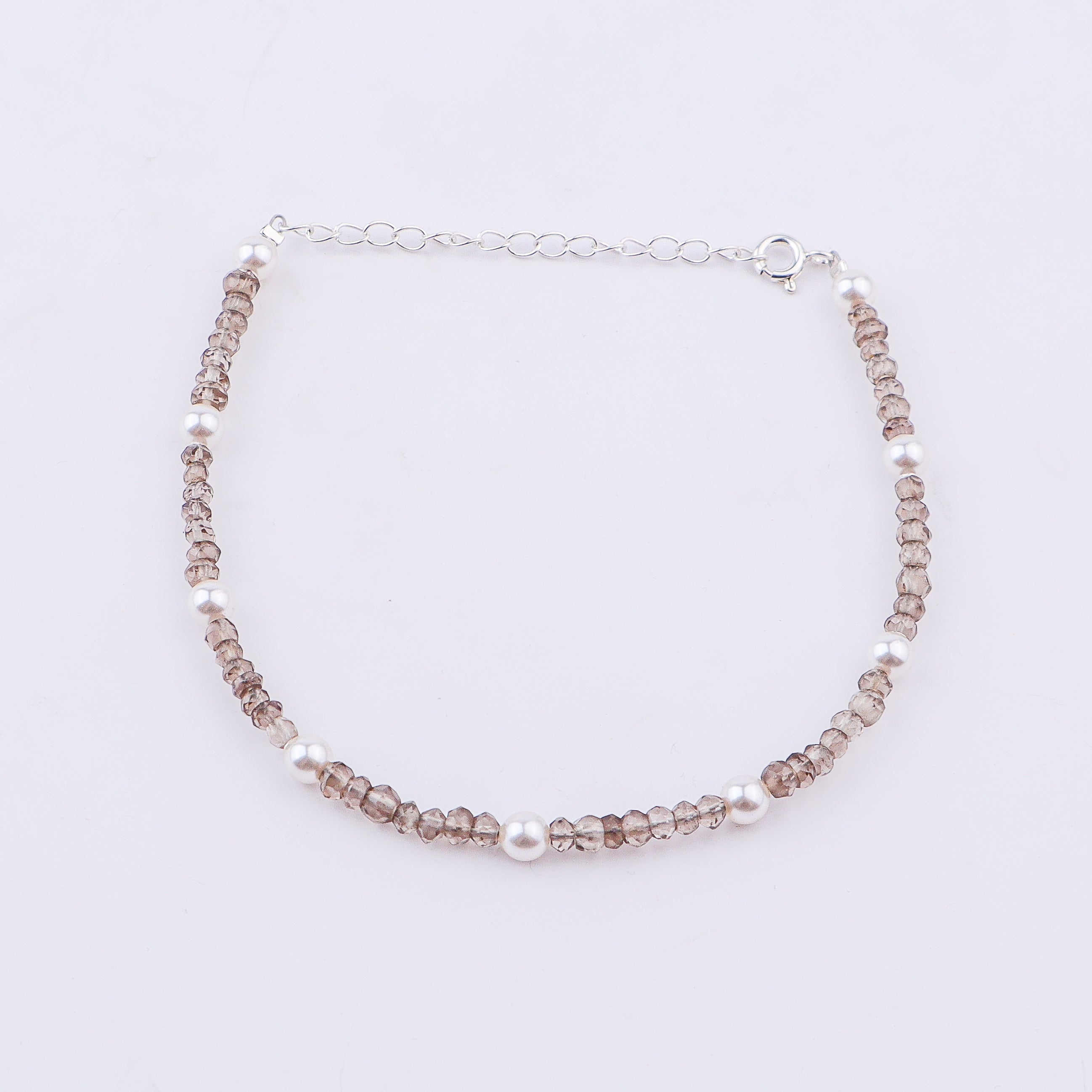 Silver anklet with pearls and faceted beads on white background