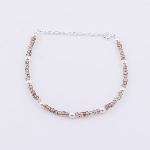 Silver anklet with pearls and faceted beads on white background