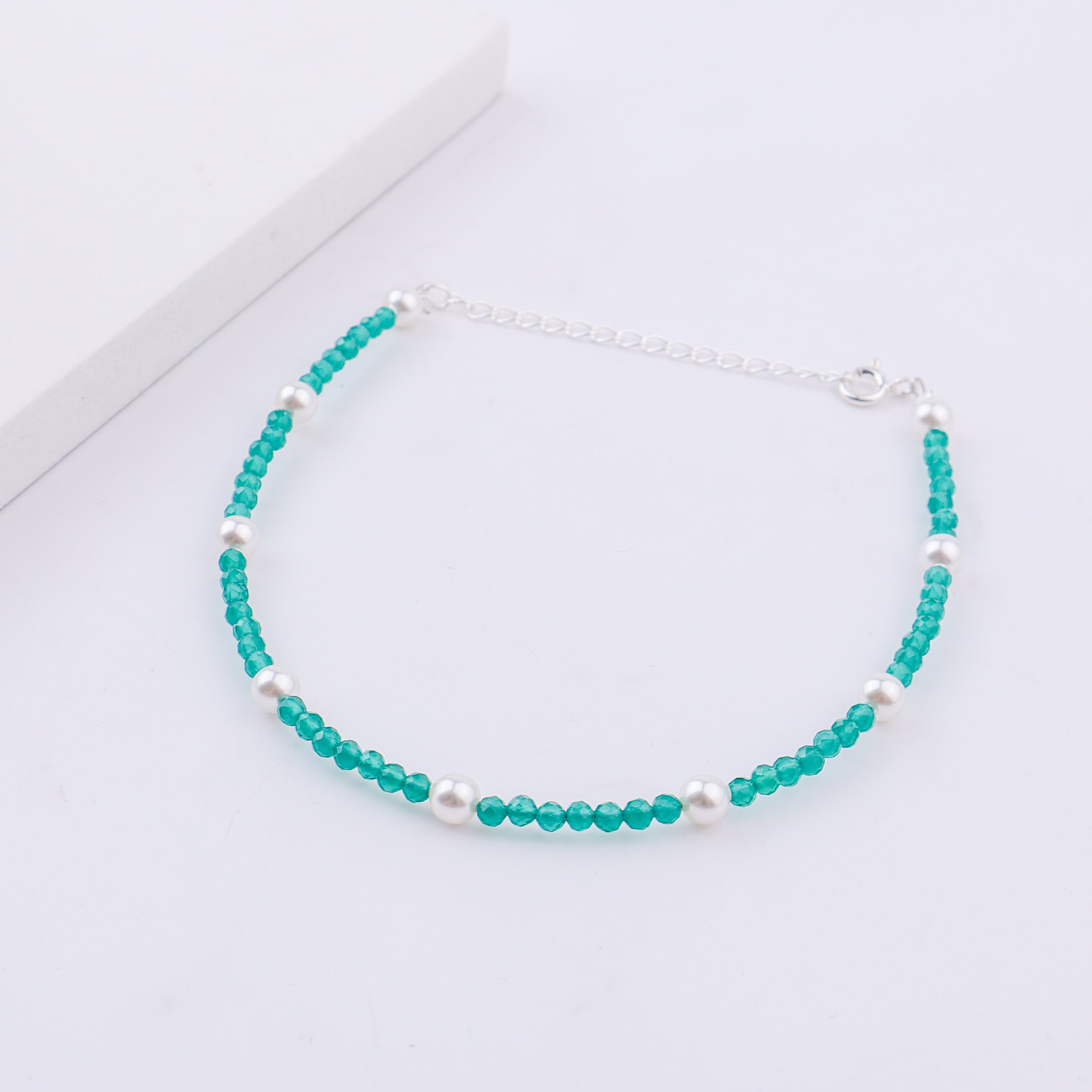 Elegant turquoise and pearl anklet on white surface