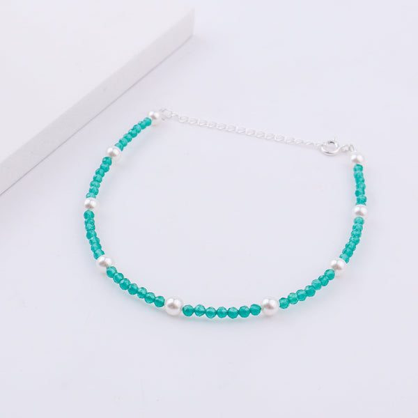 Elegant turquoise and pearl anklet on white surface