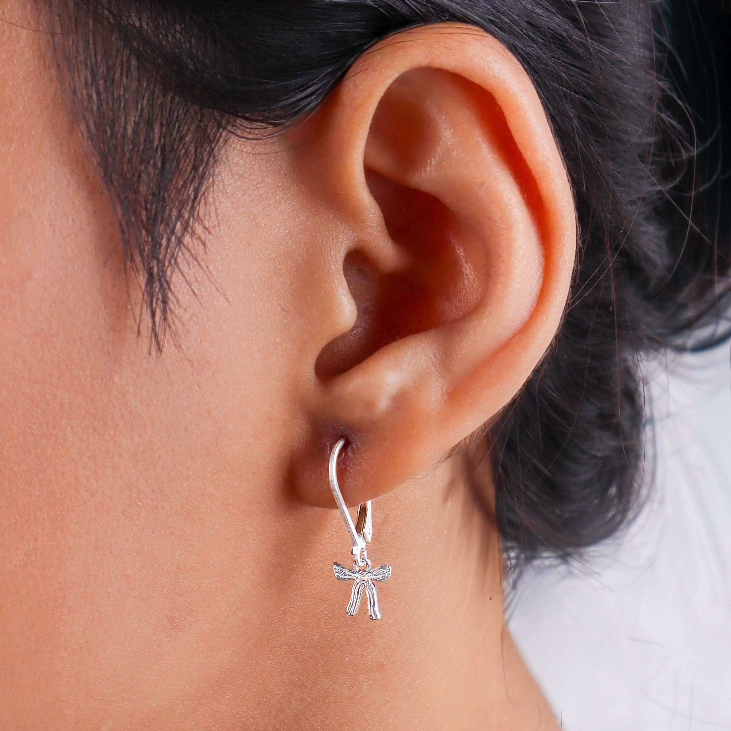Close-up of a woman's ear with silver bow earrings