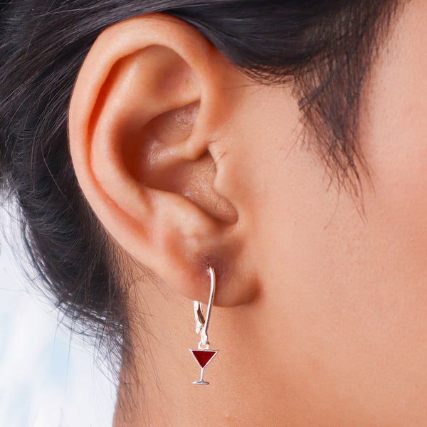 Close-up of silver earrings with red triangle charm and hook design