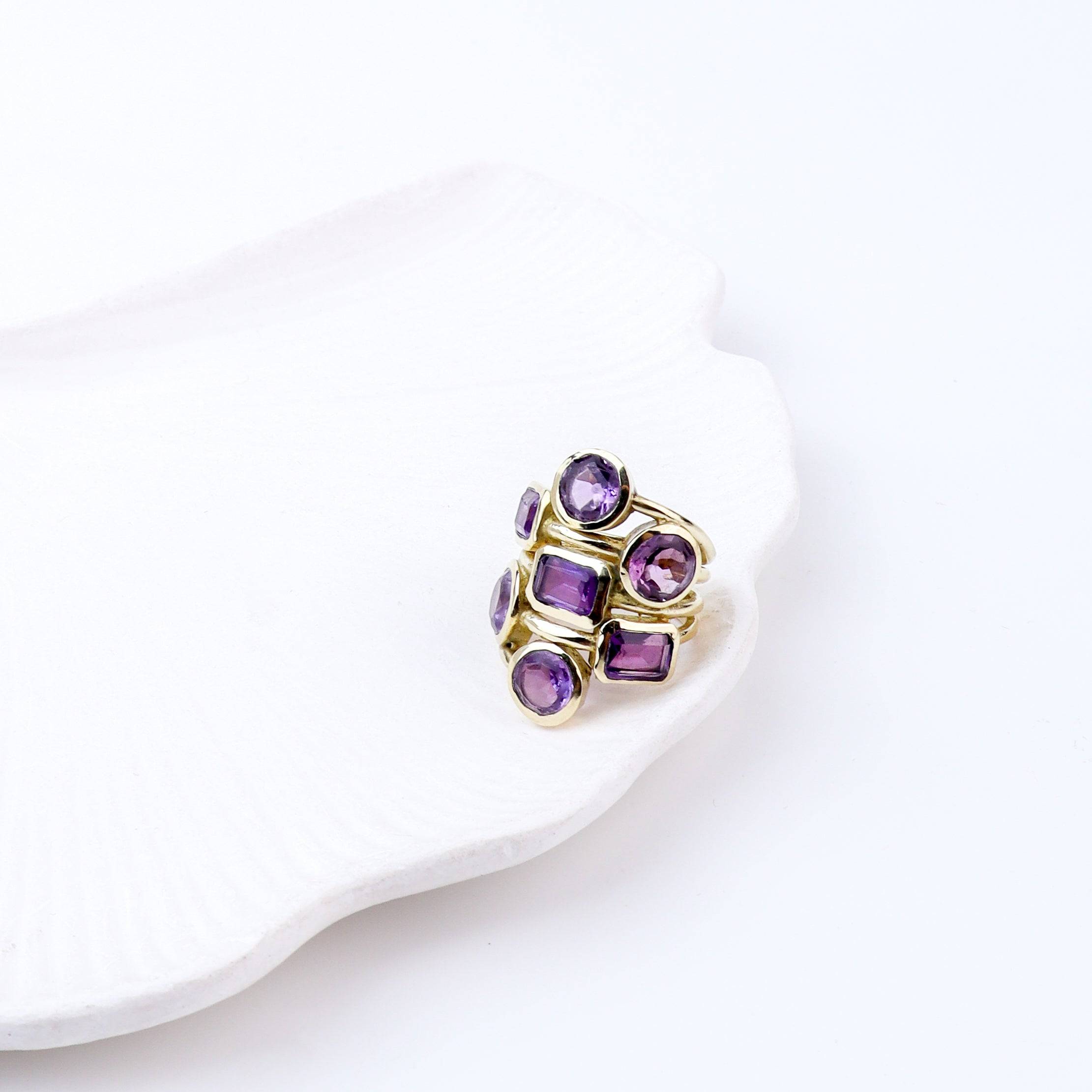 Angled view of a brass fashion ring highlighting its distinctive shape, structure, and polished brass finish
