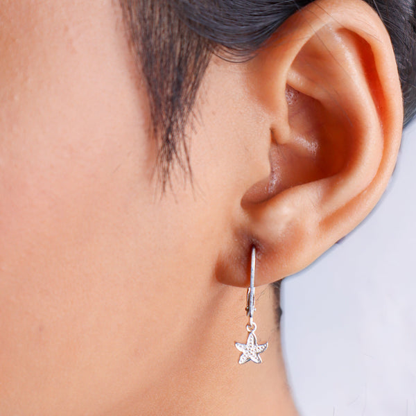 Close-up of silver starfish earrings on a person's ear