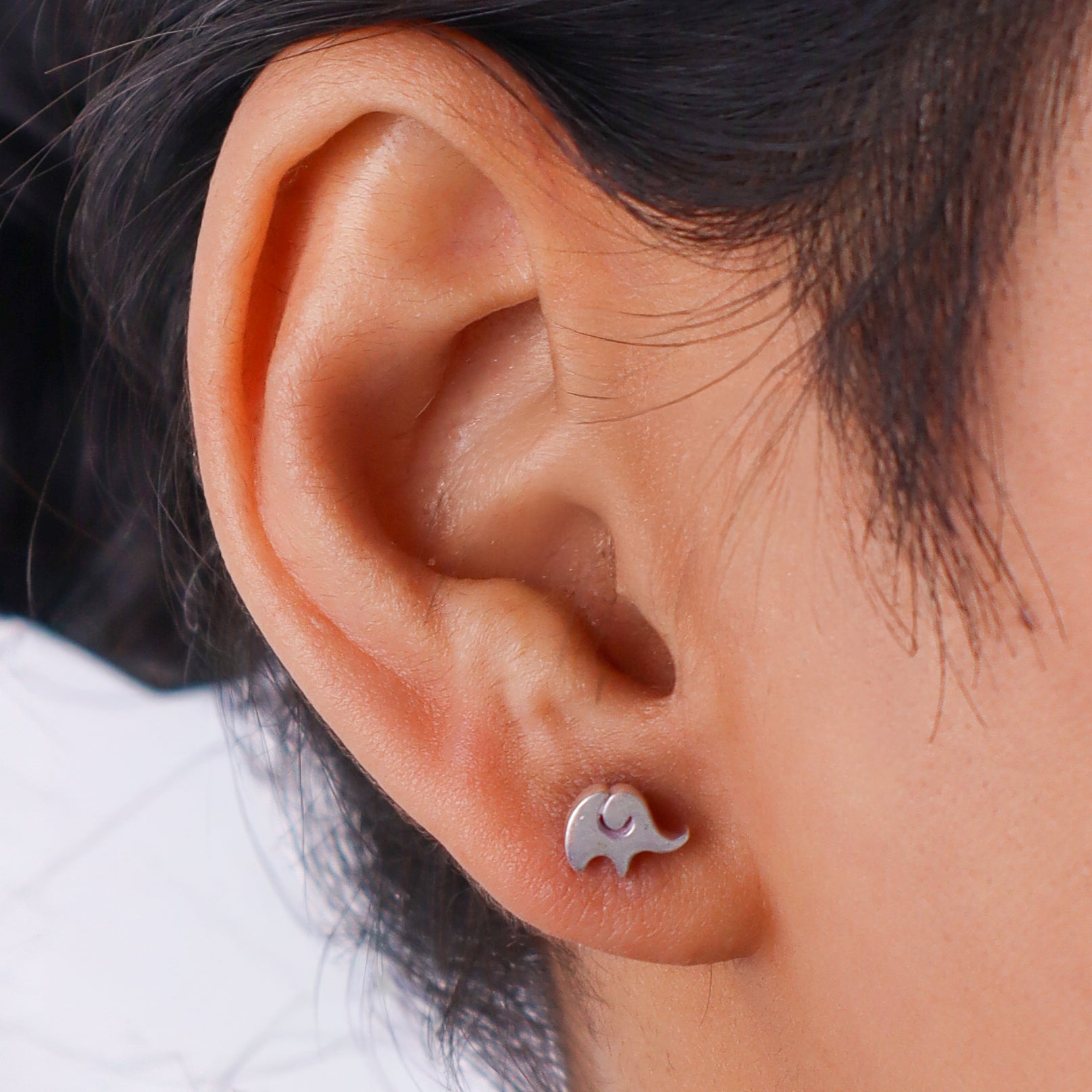 Woman wearing silver elephant stud earrings