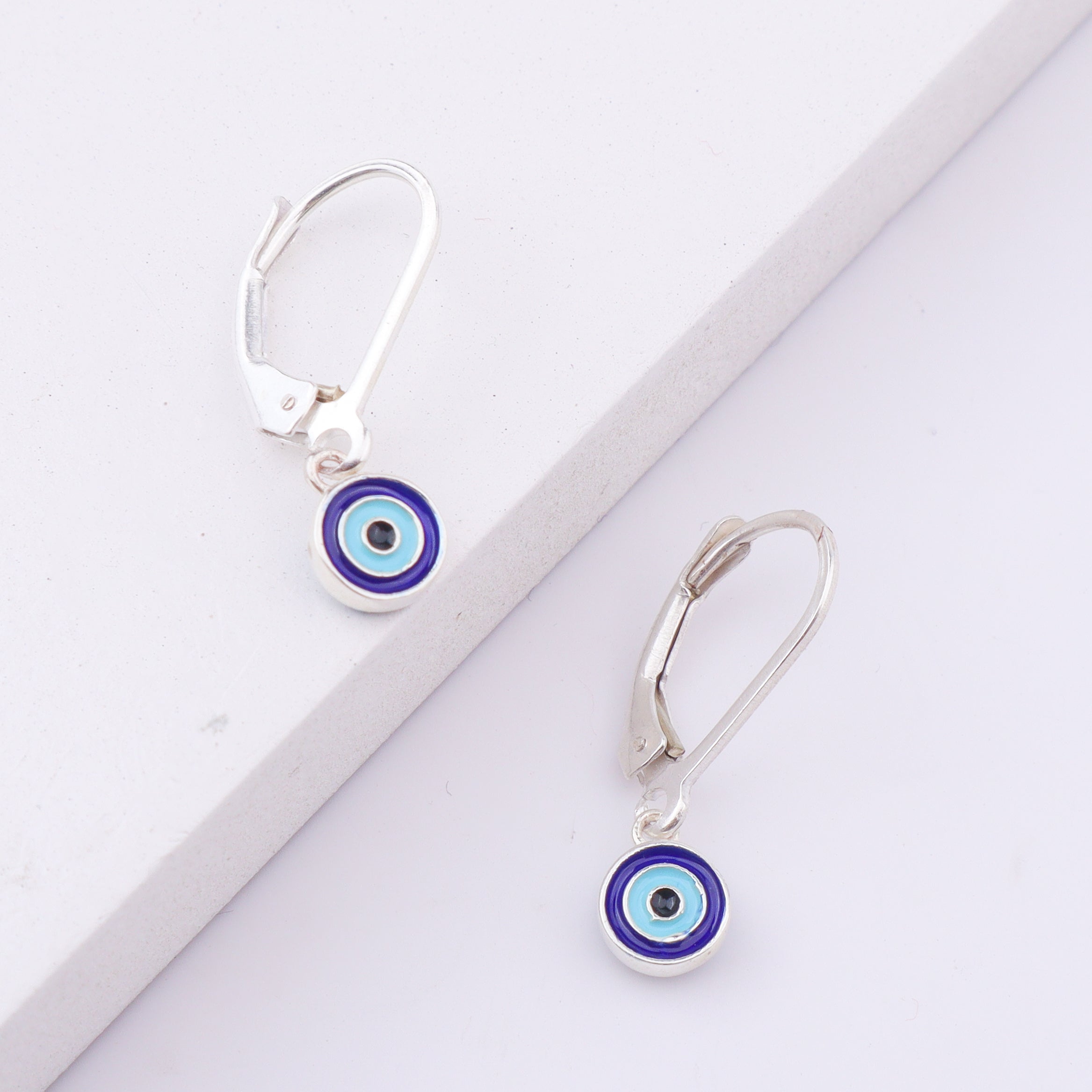 Silver earrings with evil eye design on white background