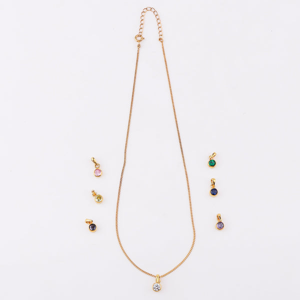 Gold chain jewelry with black cubic zirconia pendant on white background