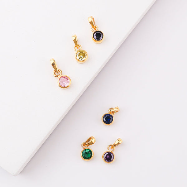 Gold chain necklace with yellow cubic zirconia pendant on white surface