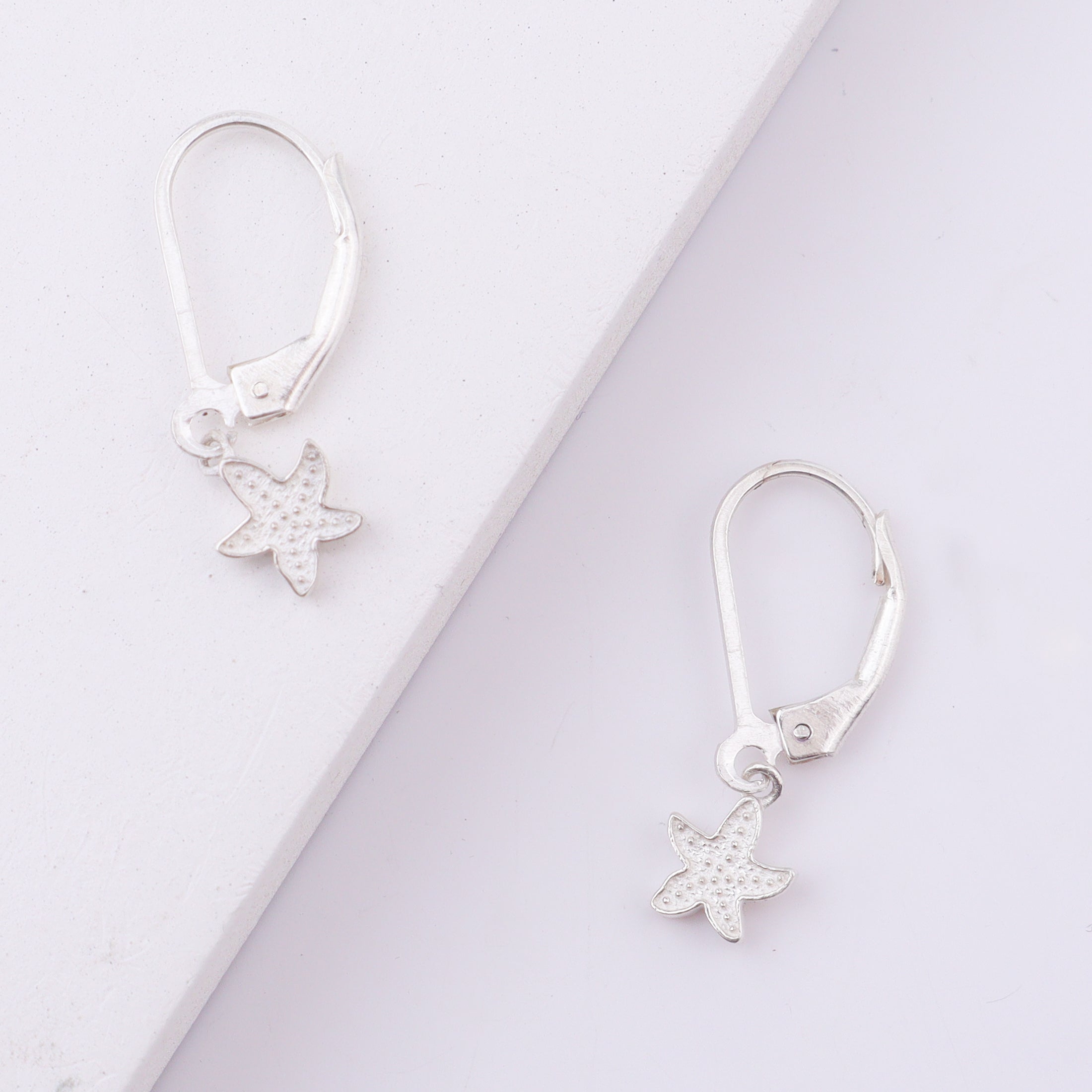 Silver starfish earrings on white background