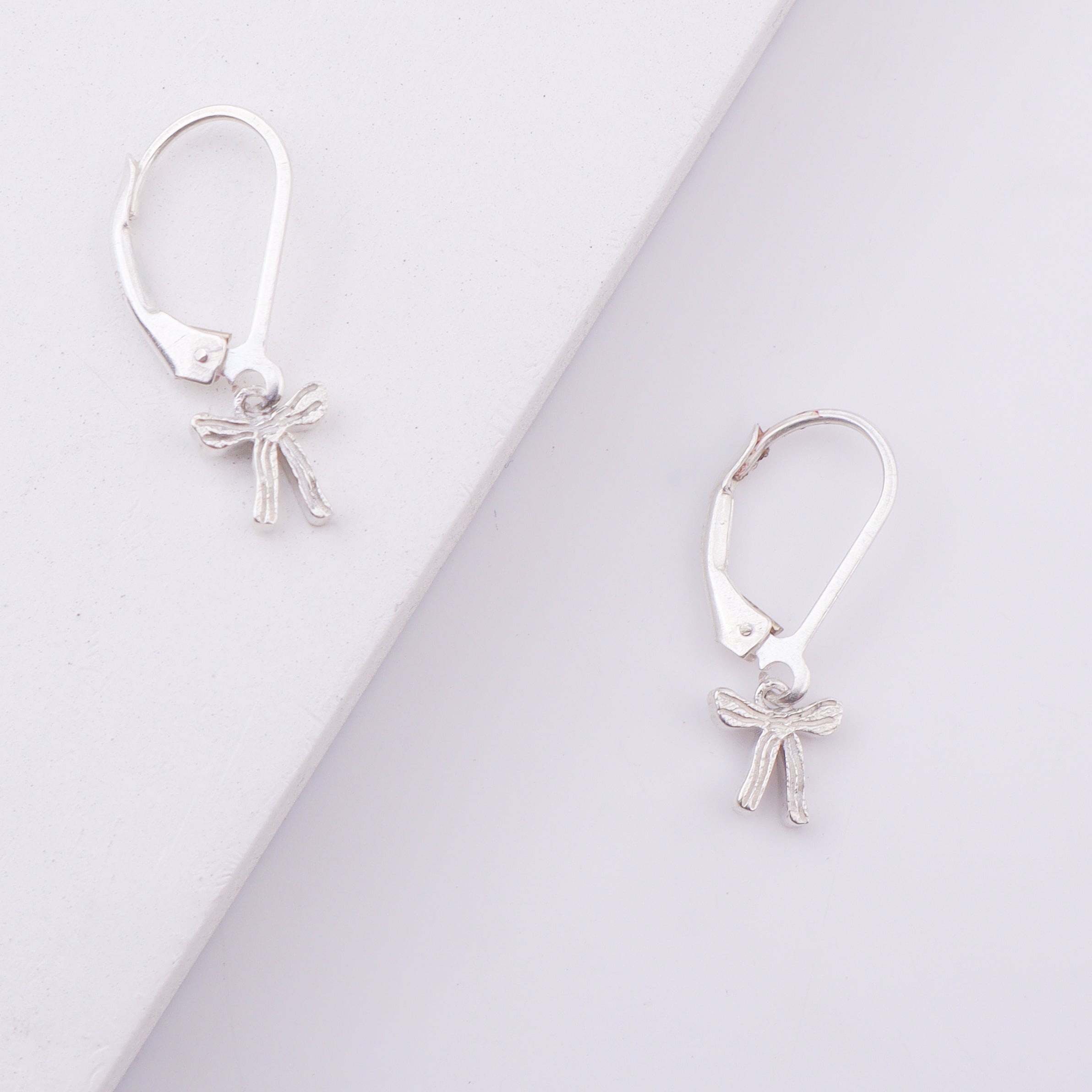 Silver bow earrings on white background
