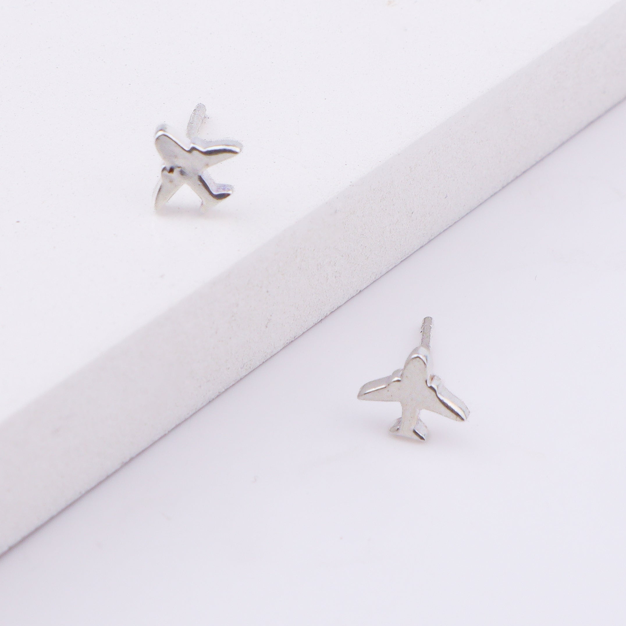 Back view of airplane silver earrings on white background