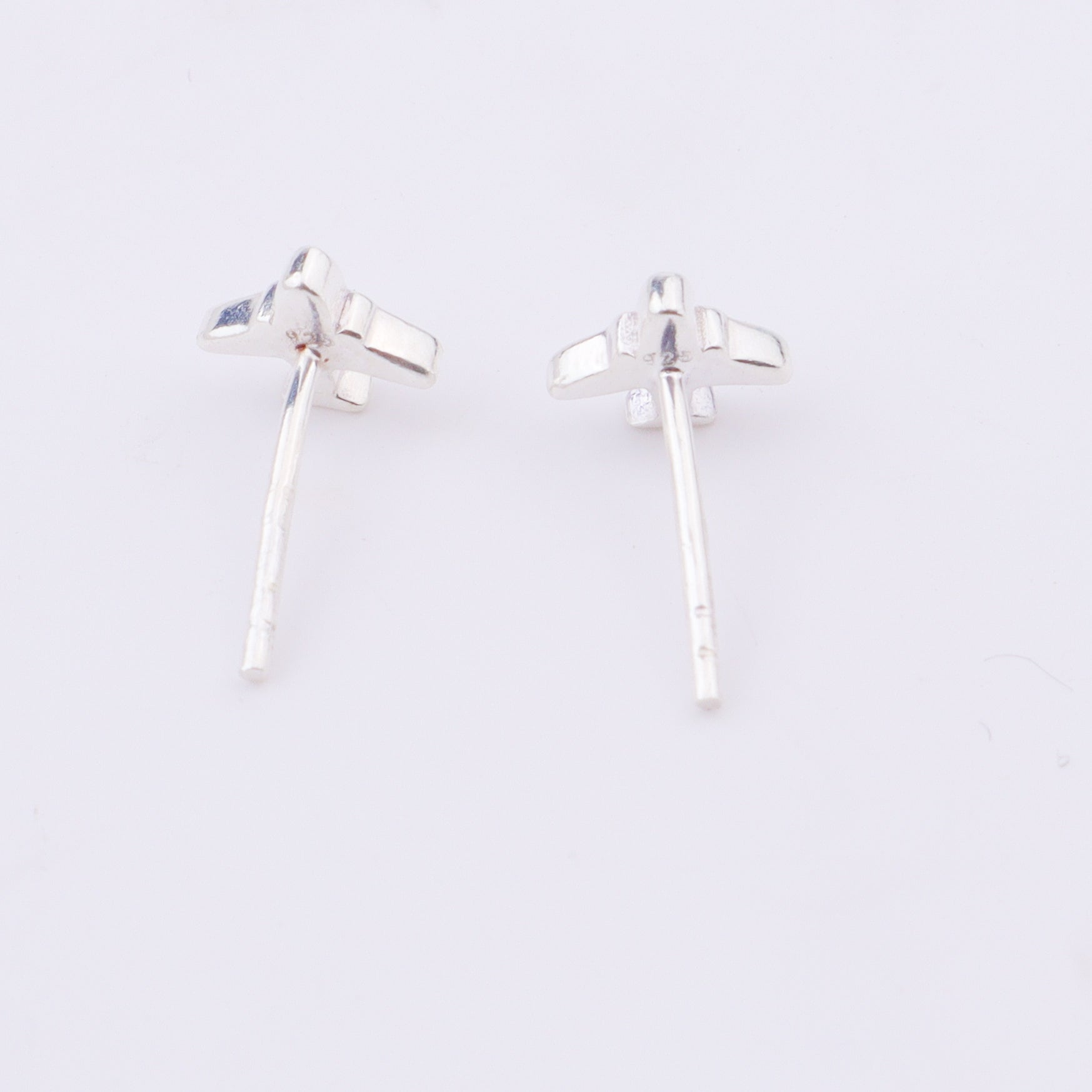 Silver airplane earrings on white display with close-up