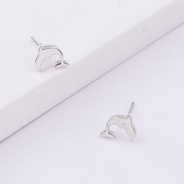 Silver dolphin stud earrings on white surface